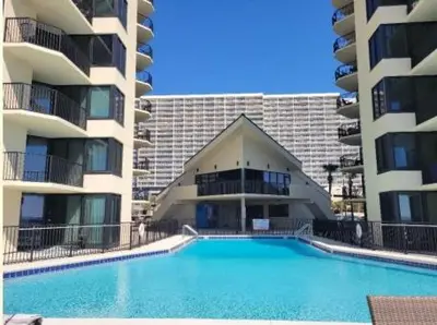 a swimming pool in front of two apartment buildings at Sunbird Resort - 11th Floor - Free Beach Chairs - by Sunbird Rentals in Panama City Beach