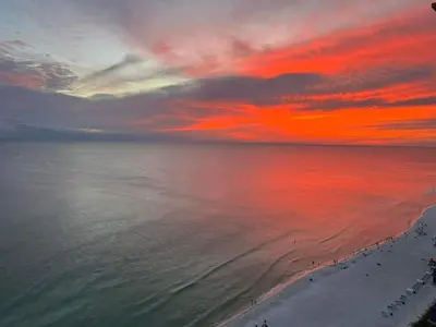 a sunset over the ocean with people on the beach at Romantic Beachfront Sunsets in Panama City Beach