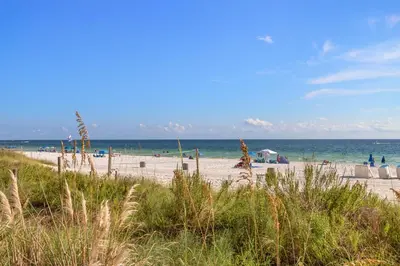 a beach with people and the ocean in the background at It Doesn’t Get Any Better Than This! 2BR 2BA Sleeps 8 Beachfront! in Panama City Beach