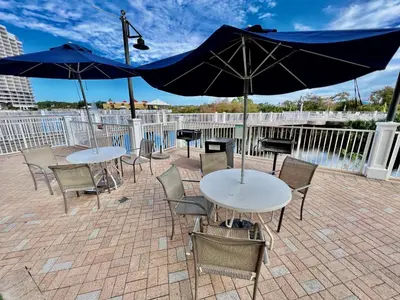 two tables and chairs with umbrellas on a patio at Bright & Spacious Condo 1BD! Steps from the Beach! by Dolce Vita Getaways PCB in Panama City Beach