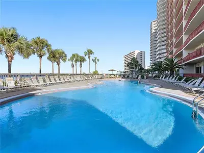 a large swimming pool with chairs and palm trees at Hidden Dunes 704 in Panama City Beach