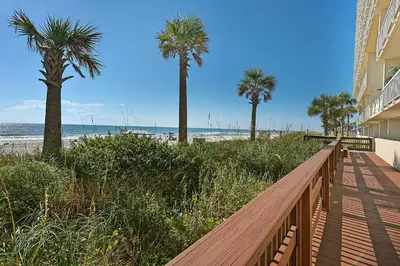 a wooden walkway to the beach with palm trees at Celadon 2005 by Emerald Coast Retreats in Panama City Beach