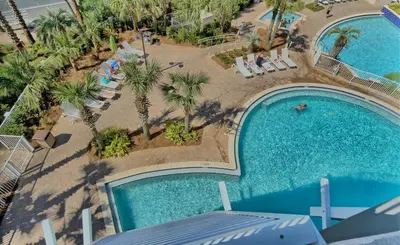an overhead view of a pool with chairs and palm trees at Spacious 3BR + Bunk Laketown Wharf Condo Sleeping 10 Near Beach in Panama City Beach