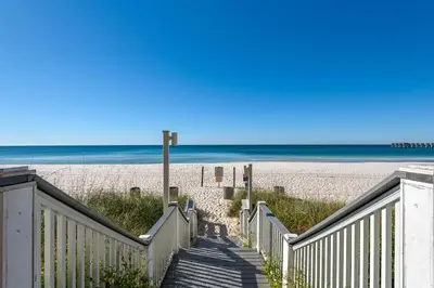 a stairway leading to a sandy beach with the ocean at Calypso 1-202 by Emerald Coast Retreats in Panama City Beach