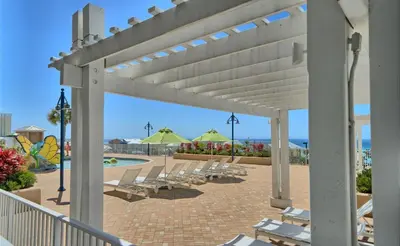 a row of lounge chairs on a patio with a pool at Resort-Style Lake-View Condo, 5 Pools, Hot Tubs, Walk to Beach in Panama City Beach