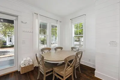 a dining room with a table and chairs and windows at Om Sweet Om in Seagrove Beach