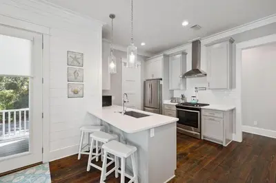 a kitchen with white cabinets and a kitchen island with stools at Om Sweet Om in Seagrove Beach