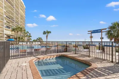 a swimming pool with a fence next to a resort at Commodore 0201 in Panama City Beach