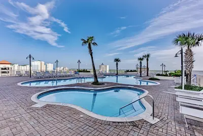 a large swimming pool with palm trees in a resort at Beach Resort Condo with 5 Pools! Steps to Beach! by Dolce Vita Getaways PCB in Panama City Beach