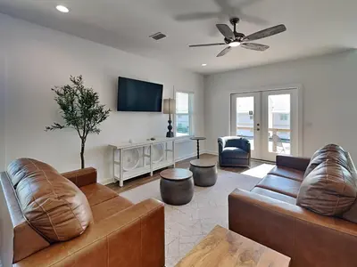 a living room with two leather couches and a flat screen tv at Sunset on Snapper C in Panama City Beach