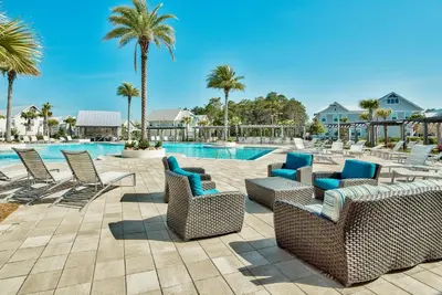 a patio with chairs and a pool with palm trees at Pet Friendly - Prominence on 30A by Panhandle Getaways in Watersound Beach
