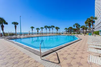 a swimming pool with palm trees and the ocean at Summit 627 in Panama City Beach