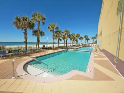 a swimming pool with palm trees and the beach at Sterling Reef 405 by Emerald Coast Retreats in Panama City Beach