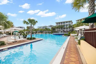 a swimming pool at a resort with palm trees at Tram-on-Time Carriage House by 30A Escapes in Rosemary Beach