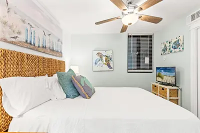 a bedroom with a white bed and a ceiling fan at Perching Pretty at Sunbird in Panama City Beach