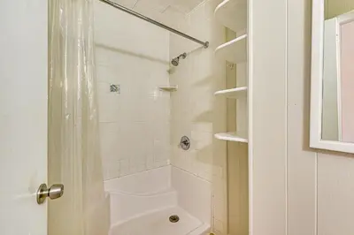 a white bathroom with a shower and a toilet at Steps to Sand! PCB Haven with Furnished Outdoor Area in Panama City Beach