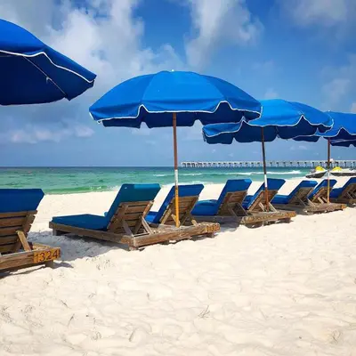 a row of blue chairs and umbrellas on a beach at Origins at Seahaven 1504 in Panama City Beach