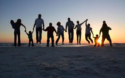 a group of people walking on the beach at sunset at Origins at Seahaven 1429 in Panama City Beach