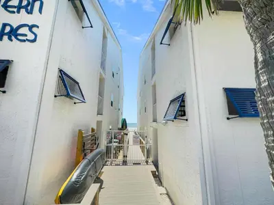 a hallway between two buildings with a inflatable boat on it at Endless Waves 208 l Beachfront l Stunning Beach Views l Bike to Seaside in Santa Rosa Beach
