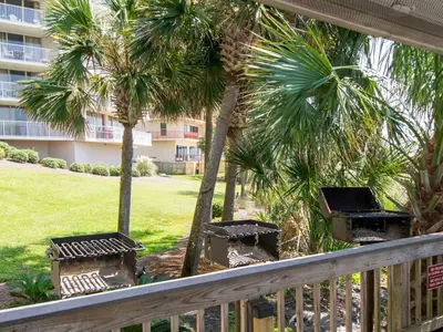 a balcony with palm trees and benches and a building at Dunes of Panama #B301 in Panama City Beach
