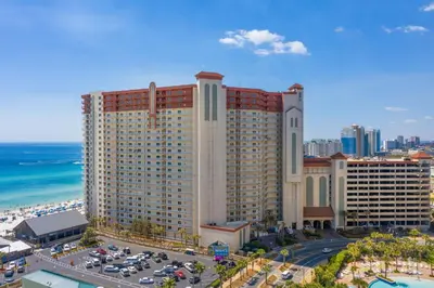 a large building with cars parked in a parking lot at Shores of Panama Ground Floor Unit 108! No elevators needed and convenient same-floor parking! in Panama City Beach