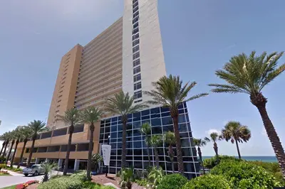 a large building with palm trees in front of the ocean at Sterling Reef 301 by Emerald Coast Retreats in Panama City Beach