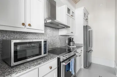 a kitchen with white cabinets and a microwave at YOLO Carriage in Rosemary Beach