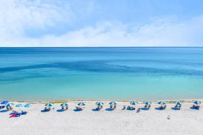 a group of chairs and umbrellas on a beach at Gulf Vista Condominiums in Seacrest