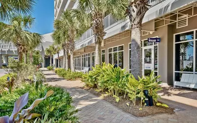 a building with palm trees in front of it at Gulf-View Resort Condo with Pools & Beach Access by Dolce Vita Getaways in Panama City Beach