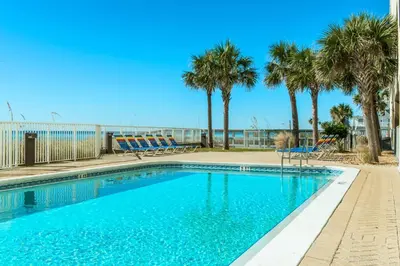 a swimming pool with palm trees and chairs at Ocean Reef 2203 by Emerald Coast Retreats in Panama City Beach