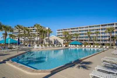 a large swimming pool with chairs and a resort at Dunes of Panama C104 - First Floor Gem in Panama City Beach