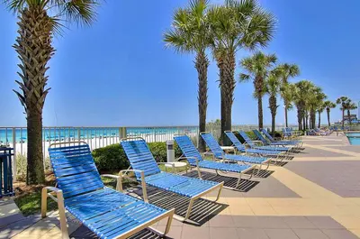 a row of blue beach chairs next to the beach at Sterling Reef 104 in Panama City Beach
