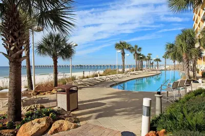 a swimming pool with palm trees and a beach at Calypso 2-404 by Emerald Coast Retreats in Panama City Beach