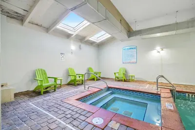 a pool in a room with green chairs and a table at Shores of Panama 530 in Panama City Beach