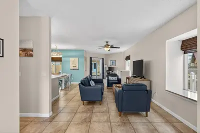 a living room with blue chairs and a table at Emerald Escape - 3 Blocks to Beach in Panama City Beach