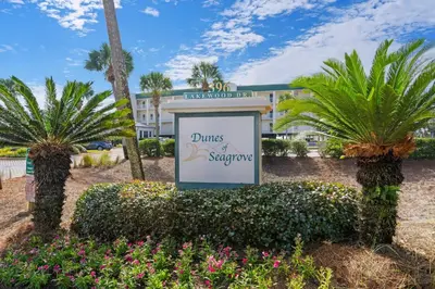 a sign in front of a building with palm trees at First-floor condo with sauna gym pool tennis & pickleball in Santa Rosa Beach