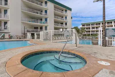a small pool in front of a apartment building at Two-bedroom with bunks balcony overlooking pool & on-site pickleball in Santa Rosa Beach