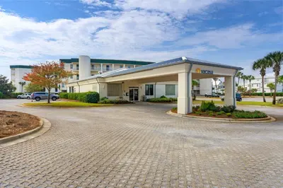 a building with a parking lot in front of it at 4th-floor condo with beach ambience lagoon pool gym tennis & pickleball in Santa Rosa Beach