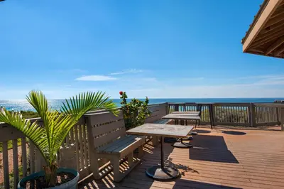 a wooden deck with a table and benches on the beach at Elegant getaway with stunning view lagoon pool & pickleball - close to shops in Seacrest