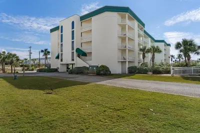 a large white building with palm trees in front of it at Lovely home with pool & Gulf views covered parking bikes & pickleball in Santa Rosa Beach