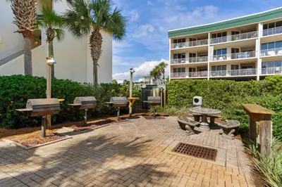 a patio with benches and picnic tables in front of a building at Lovely home with pool & Gulf views covered parking bikes & pickleball in Santa Rosa Beach