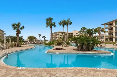 a swimming pool with palm trees and buildings at Gorgeous home with tennis pickleball pool & hot tub - steps from the beach in Seacrest