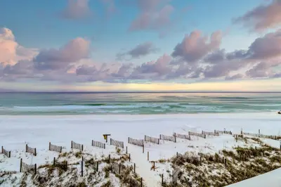 a beach with a fence in the sand at Lovely first floor condo with ocean views patio & grill - steps from the beach in Santa Rosa Beach