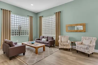 a living room with chairs and a table at Beach haven with patio lagoon pool hot tub & pickleball - walk to beach in Seacrest