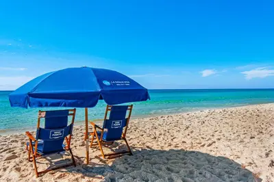 two chairs and an umbrella on a beach at Lavish High Pointe condo with resort pool amazing ocean view & pickleball in Seacrest