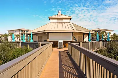 a boardwalk leading to a house with a building at Water-view condo with pool hot tub & pickleball in Rosemary Beach