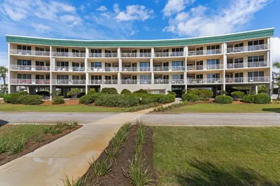 a large white building with a green roof at Beach-view condo with outdoor pool hot tub sauna tennis BBQ & beach access in Santa Rosa Beach