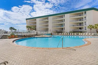 a swimming pool in front of a large building at Ground floor beachfront condo with shared pool and beach access in Santa Rosa Beach
