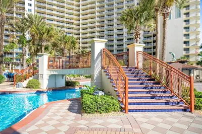 a staircase leading to a pool with palm trees and a building at Shores of Panama 2112 in Panama City Beach