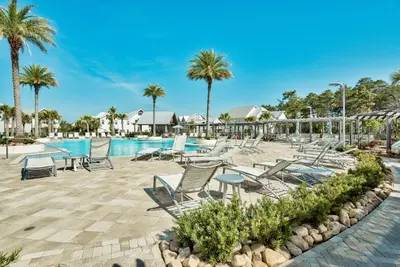 a pool at a resort with chairs and palm trees at Prominence on 30A Beach Homes by Panhandle Getaways in Watersound Beach
